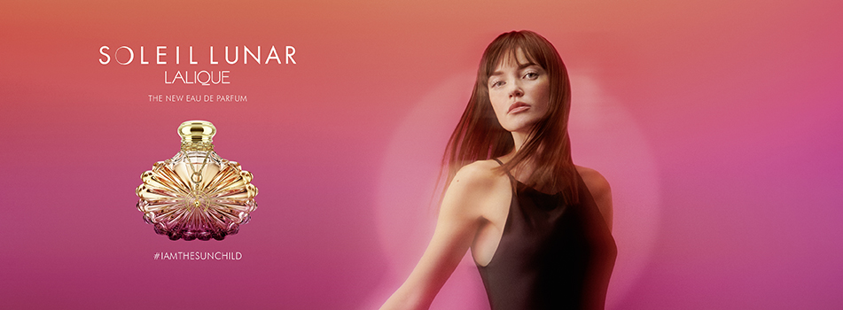 Werbemotiv für das Parfum „Soleil Lunar“ von Lalique. Links im Bild ist ein elegant geschliffener, gold-pinker Flakon zu sehen, darüber steht der Schriftzug „Soleil Lunar – The new Eau de Parfum“. Rechts blickt eine Frau mit langen braunen Haaren in einem schwarzen Kleid in die Kamera. Der Hintergrund ist in warmen Farbverläufen von Rot über Pink bis Violett gehalten. Unten steht der Hashtag „#IAMTHESUNCHILD“.