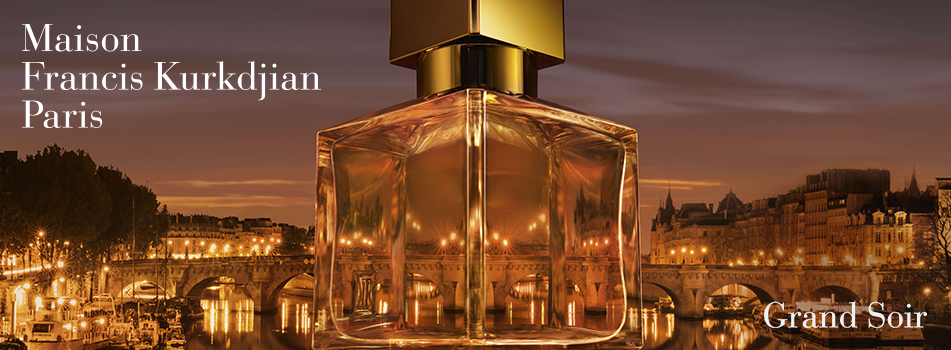 Werbebild für das Parfüm ‚Grand Soir‘ von Maison Francis Kurkdjian Paris. Ein goldener Flakon steht im Vordergrund vor einer abendlichen Stadtansicht von Paris mit beleuchteter Brücke und warmem Licht. Links oben der Markenname ‚Maison Francis Kurkdjian Paris‘, rechts unten der Duftname ‚Grand Soir‘.